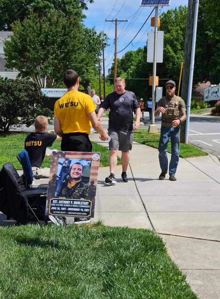 Supporters walking together, carrying photos of loved ones lost to military suicide