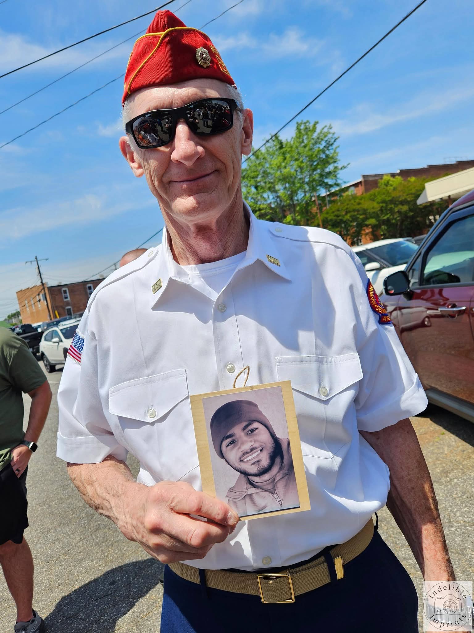 A Marine Corps League member holding a memorial photo of a fallen service member