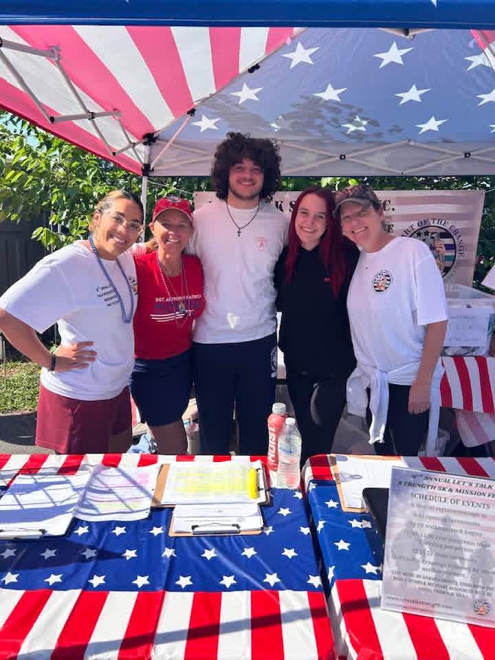 Volunteers smiling together at the Let's Talk Strength 5K & Mission Fest registration tent