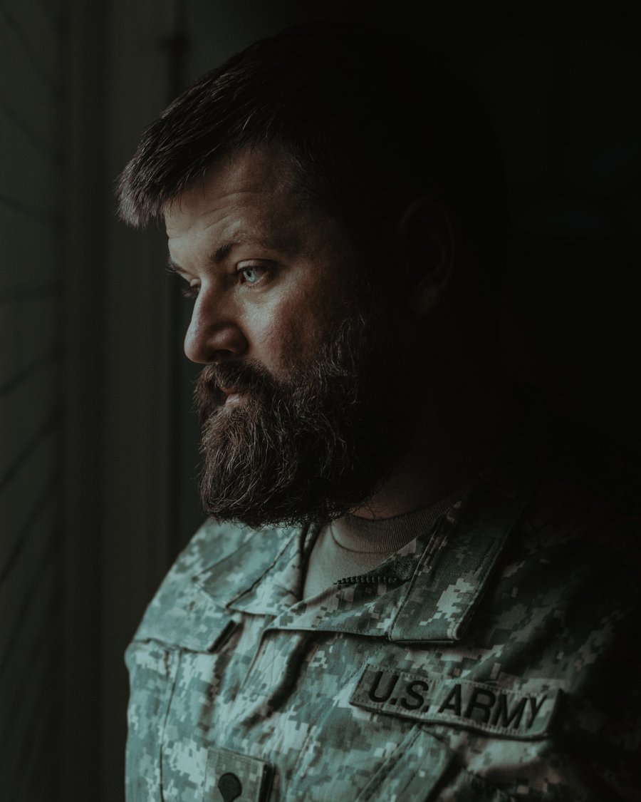 A close portrait of a bearded veteran in digital camouflage